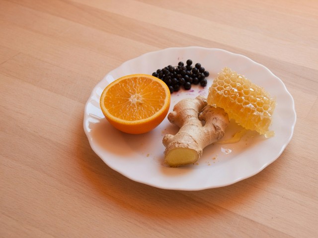 Naranja, jengibre, bayas de saúco y panal sobre una mesa de madera: motivos de la lista de ingredientes