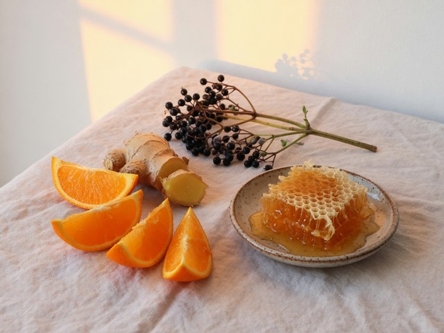 Gomos de laranja, gengibre fresco, bagas de sabugueiro e favo de mel sobre um pano de linho: motivos da lista de ingredientes